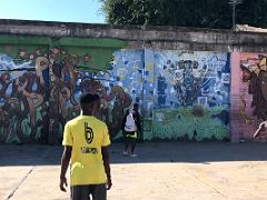 03C Kids play ball in the abandoned warehouse with murals behind at the home of Paint Jamaica street art in Kingston Jamaica